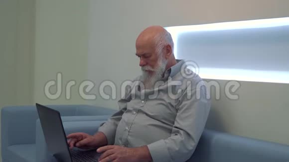 老人在候诊室等候时使用笔记本电脑视频的预览图