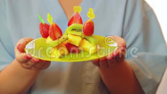 那个女人厨师微笑着拿着一个盘子手里拿着一份水果甜点控制来自窗户的阳光特写镜头视频的预览图
