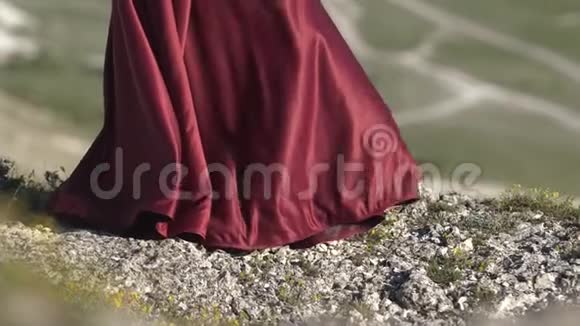 年轻的女孩在风中握住紫色裙子的下摆织物的褶皱被倒入阳光中视频的预览图