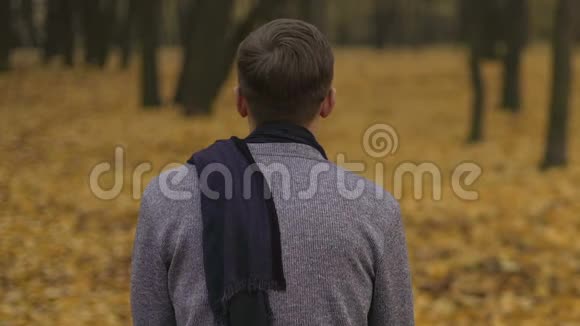 悲伤的年轻人独自坐在阴暗的秋天公园里感到不快乐和孤独视频的预览图