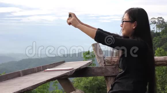 亚洲女性在大自然背景下用手机或智能手机拍摄照片视频的预览图