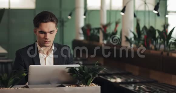 疲惫的年轻商人坐在咖啡馆里用笔记本电脑工作自由沟通IT疲惫的商人视频的预览图