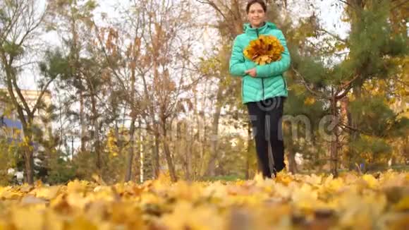 女孩走过秋天的公园用脚捧着金色的枫叶视频的预览图