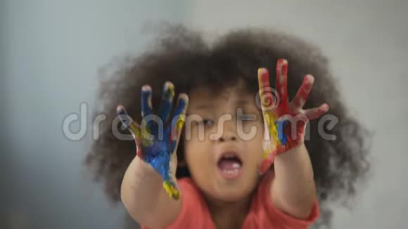 开朗的非裔美国女孩玩得开心把画好的手掌拍成相机视频的预览图