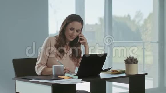 商业女性在笔记本电脑上工作专心致志的女士在说电话视频的预览图