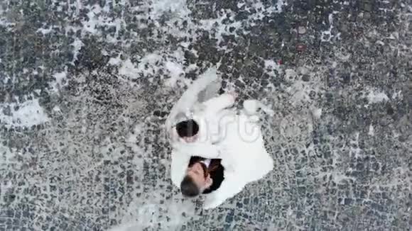 冬季婚礼身着婚纱的新婚夫妇在白雪覆盖的公园里跳着婚礼舞视频的预览图