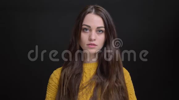 穿着黄色毛衣的年轻黑发白种人女孩用黑色镜头认真观看的肖像视频的预览图