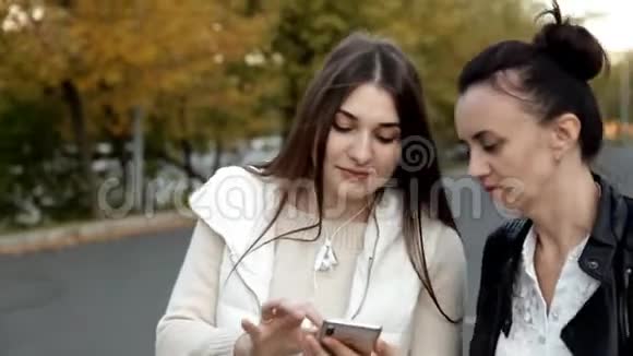 两个女孩走在街上聊天然后进了绿色的车视频的预览图
