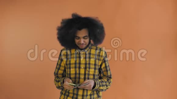 年轻的非裔美国人在橙色背景上数现金钱视频的预览图