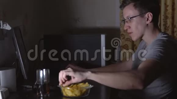 年轻人坐在电脑前吃薯片视频的预览图