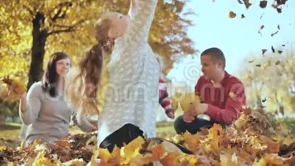 在阳光明媚的秋天天气里快乐的一家人在户外玩落叶视频的预览图