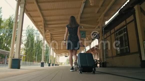 黑衣女子提着手提箱走在火车站的背影视频的预览图