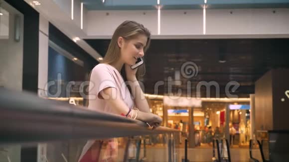 年轻迷人的女孩站在商场里打电话购物观念时尚观念交流观念视频的预览图