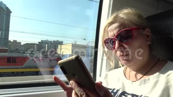 坐火车旅行的女游客女人看着智能手机看着新闻视频的预览图