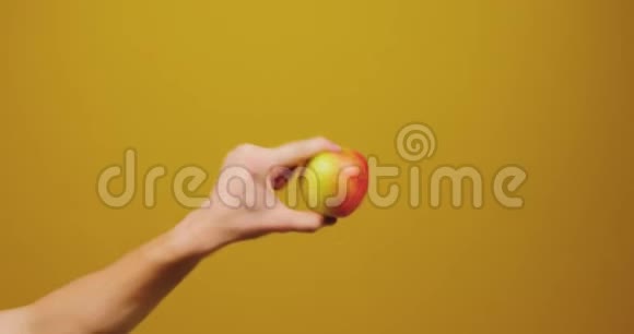 男手给了一个女人一个苹果孤立在黄色背景在工作室健康的生活方式水果健康视频的预览图