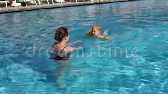 特写快乐妈妈教儿子在游泳池里游泳慢动作视频的预览图