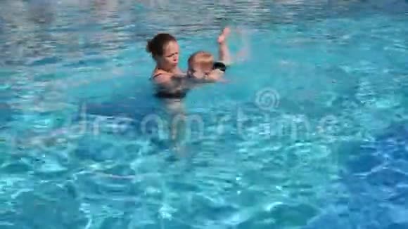 特写快乐妈妈教儿子在游泳池里游泳慢动作视频的预览图