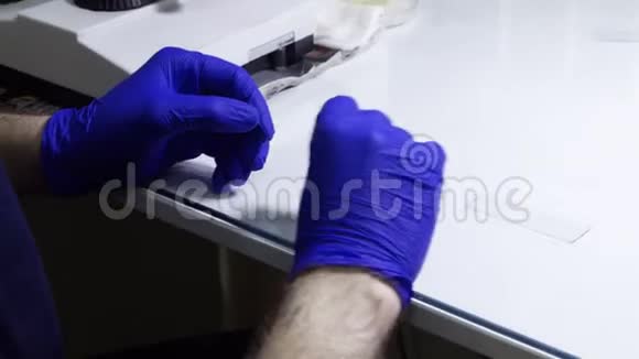 一位科学家把试管中的血样放在玻璃杯上以便在显微镜下检查视频的预览图
