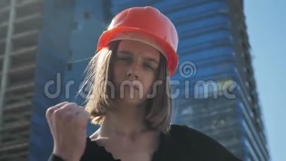 年轻的强壮的有小村庄的女建筑工人在夏天的白天表现出拳头建筑理念城市理念基础之上视频的预览图