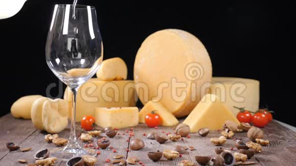 白葡萄酒被倒入一个杯子背景上有各种各样的硬奶酪食品艺术概念餐厅视频的预览图
