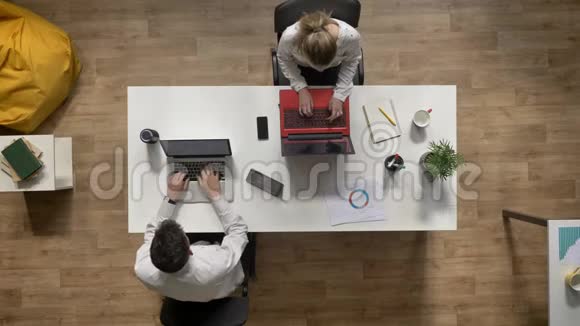 两个商人在现代办公室里工作和坐在桌子旁的时候谈论笔记本电脑工作理念视频的预览图