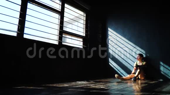 适合白色女拳击手坐在地板上靠近墙壁休息后拳击训练在健身房视频的预览图