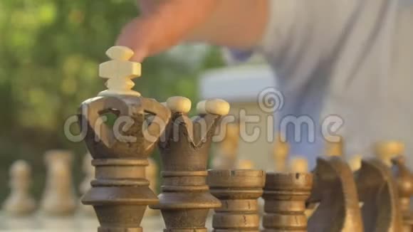 老人在桌旁的花园里准备下棋把黑色的数字放在他们的位置上视频的预览图