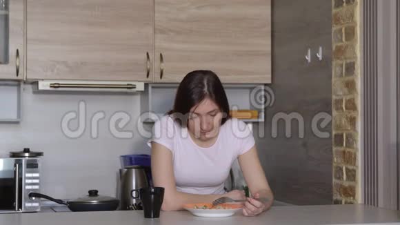 漂亮的睡眼的黑发女人在厨房吃早餐视频的预览图