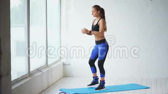 蹲下可爱的年轻女子蹲在健身室里健身房里的场景视频的预览图