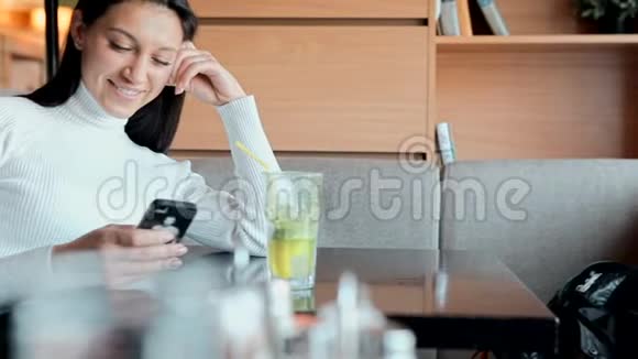 一个年轻女孩坐在咖啡店里看着电话视频的预览图