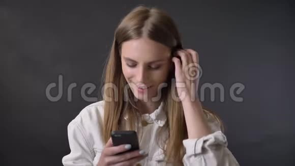 年轻酷女孩在智能手机上绑信息扎头发交流理念灰色背景视频的预览图
