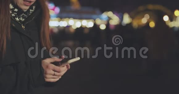 女人手使用智能手机在杜斯克市夜街灯光背景模糊视频的预览图