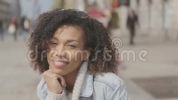 在城市街坐在长凳上的一个留着非洲发型的漂亮女孩视频的预览图