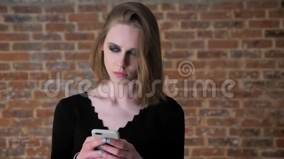 一个眼睛冒烟的年轻女孩正在智能手机上输入信息思考过程交流观念砖头视频的预览图