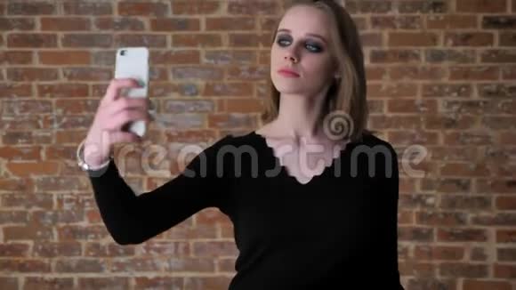 年轻迷人的女孩有着烟熏的眼睛在她的智能手机上眨眼好的标志就像标志手势概念视频的预览图