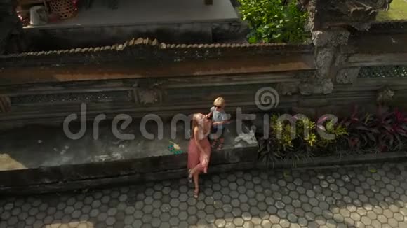 巴厘岛Ubud的PuraGunungLebah寺的楼梯上的家庭旅行者的空中射击视频的预览图
