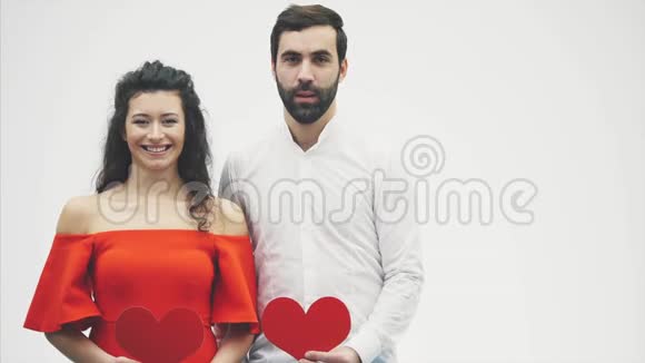 一对美丽的浪漫夫妇被隔离在白色背景下漂亮的年轻女子和英俊的男子抱着红心视频的预览图