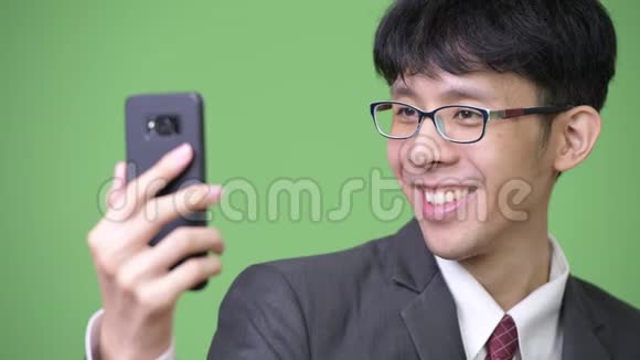 年轻快乐的亚洲商人用手机触摸屏幕视频的预览图