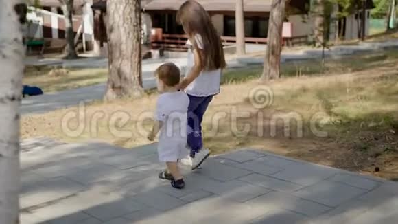 女孩帮小男孩走路视频的预览图