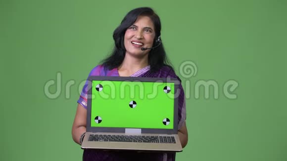 成熟快乐美丽的印度女人在展示笔记本电脑的同时代表思考视频的预览图