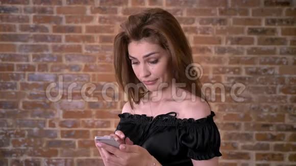 女人正在智能手机上输入信息表达情感沟通观念砖背景视频的预览图