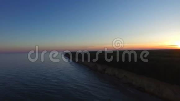 海岸线边缘的风景日落傍晚的海洋和森林背景视频的预览图