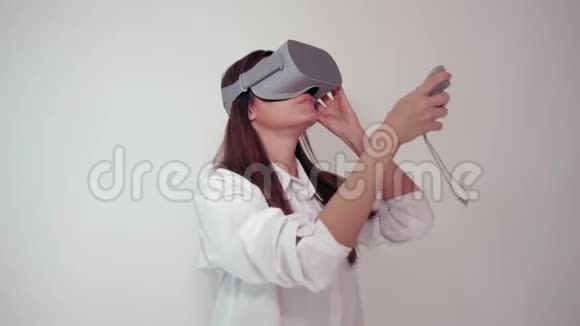 年轻的女人戴着VR耳机环顾四周想知道有多神奇白色背景下的虚拟现实头盔视频的预览图