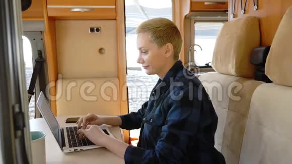 一个女人坐在汽车之家的桌子旁使用笔记本电脑视频的预览图