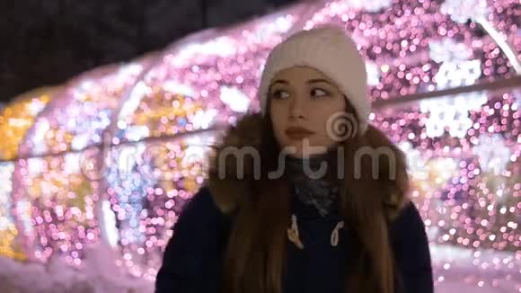 一个年轻漂亮女孩的肖像在晚上的冬天她用手套温暖双手慢动作视频的预览图