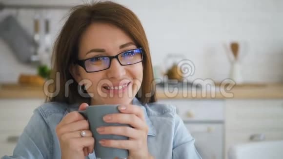 幸福的年轻女子微笑着用灰色蓝色杯子喝咖啡视频的预览图