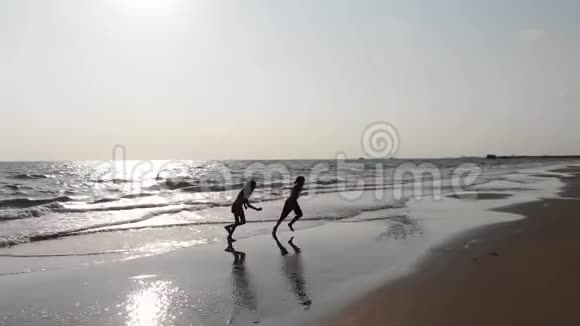 孩子们在户外的水里玩得很开心快乐的孩子们快乐的小男孩和小女孩沿着海滨奔跑视频的预览图