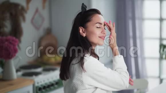 穿着浴袍的年轻女子脸上涂着奶油做面部按摩视频的预览图