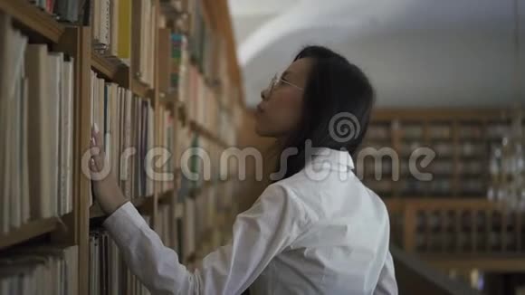 年轻的亚洲女研究员正在寻找书架上的书视频的预览图