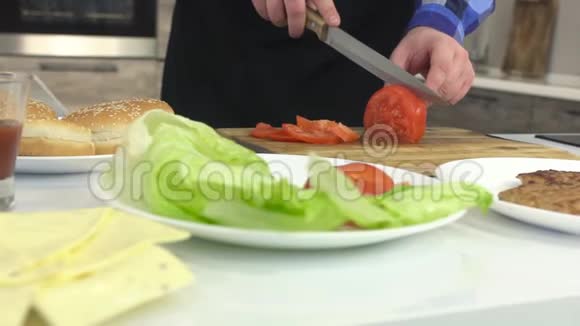 一个穿着围裙的男人在厨房里把一个西红柿切成一个盘子动作缓慢专业特写视频的预览图
